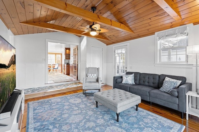 living room featuring vaulted ceiling with beams, wood ceiling, wainscoting, wood finished floors, and a ceiling fan