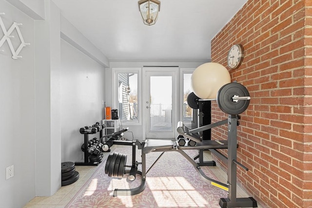 workout room featuring tile patterned flooring and brick wall