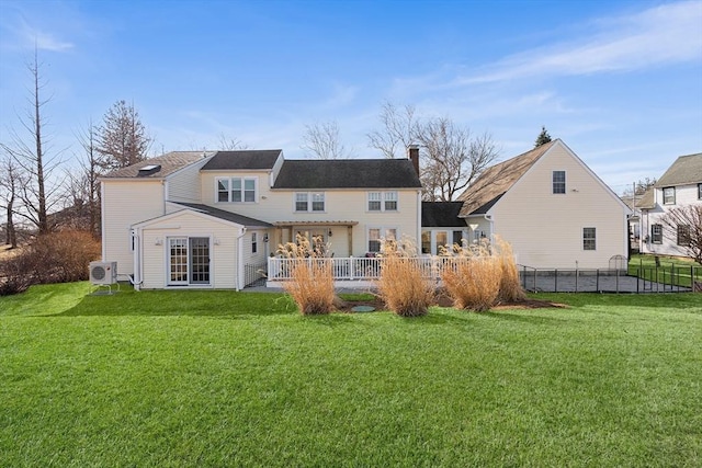 rear view of house featuring ac unit, a yard, a chimney, and fence