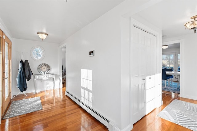 entryway with a baseboard radiator, wood-type flooring, and baseboards