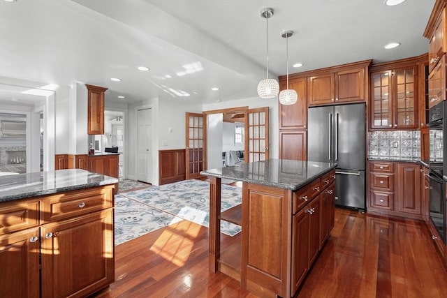 kitchen featuring a wainscoted wall, brown cabinets, high quality fridge, and a breakfast bar area