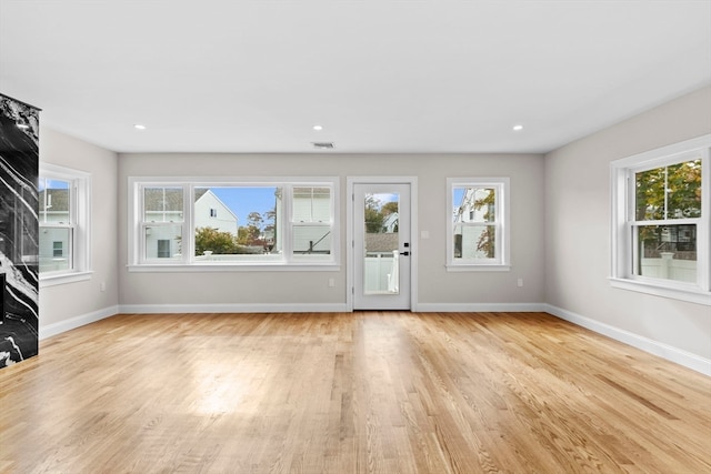 unfurnished living room with light wood-type flooring and plenty of natural light