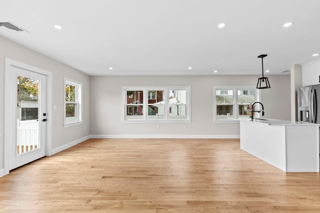 unfurnished living room with sink and light wood-type flooring