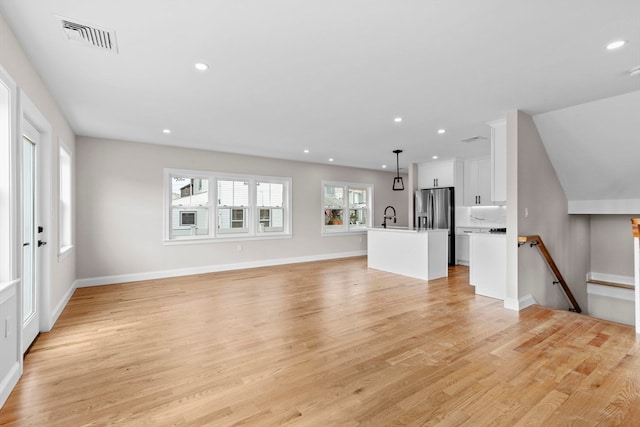 unfurnished living room featuring sink and light hardwood / wood-style flooring