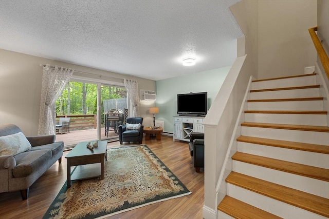 15 Roundhouse Rd Unit 15, Bourne, MA 02532 - living area featuring stairway, a textured ceiling, wood finished floors, a wall unit AC, and a baseboard radiator