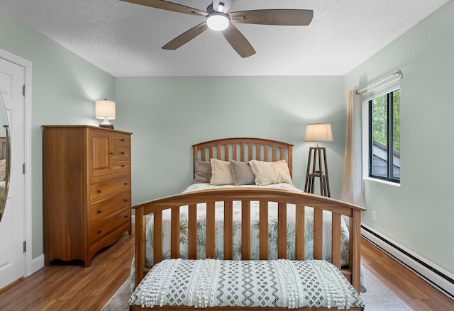 15 Roundhouse Rd Unit 15, Bourne, MA 02532 - bedroom with a baseboard radiator, wood finished floors, a textured ceiling, baseboards, and ceiling fan