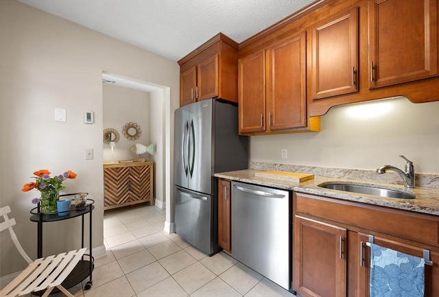 15 Roundhouse Rd Unit 15, Bourne, MA 02532 - kitchen with appliances with stainless steel finishes, a sink, brown cabinetry, light tile patterned floors, and light stone countertops