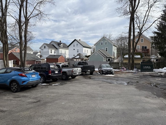 uncovered parking lot featuring fence and a residential view