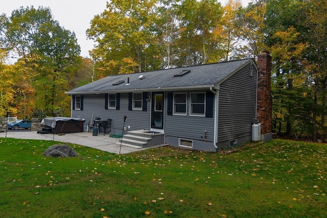 rear view of house featuring a yard, a patio area, and a hot tub