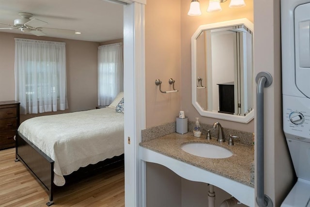 interior space with connected bathroom, a ceiling fan, a sink, and wood finished floors