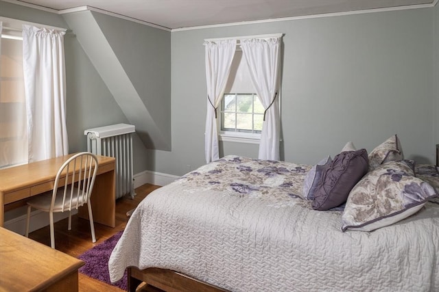 bedroom with radiator heating unit, baseboards, ornamental molding, and wood finished floors