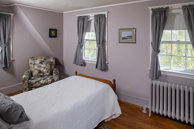 bedroom featuring crown molding, radiator, wood finished floors, and multiple windows