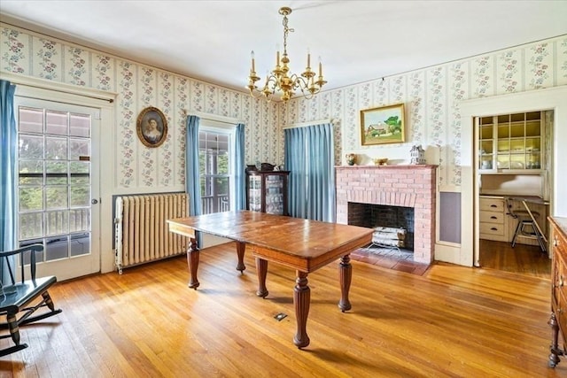 48 Neal Gate St, Scituate, MA 02066 - dining space featuring wallpapered walls, hardwood / wood-style flooring, radiator heating unit, a brick fireplace, and a notable chandelier