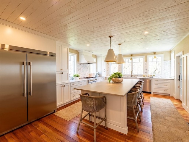 kitchen with wood-type flooring, premium range hood, light countertops, wood ceiling, and stainless steel appliances