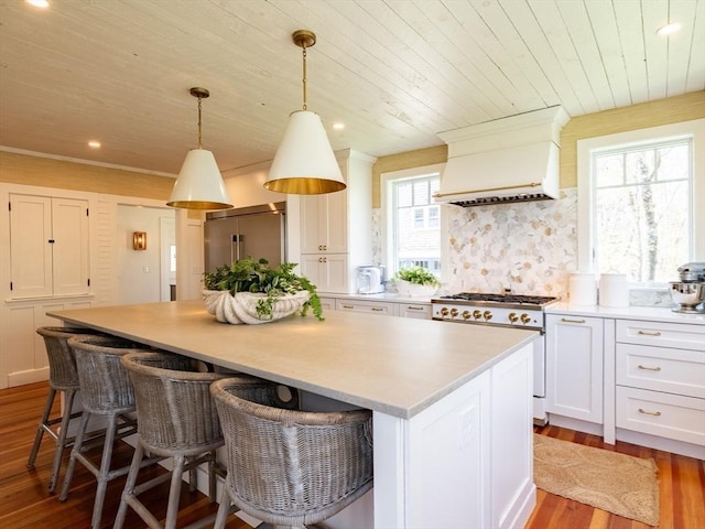 kitchen with a kitchen island, high end appliances, wood finished floors, light countertops, and wooden ceiling