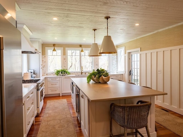 kitchen with dark wood finished floors, wood ceiling, appliances with stainless steel finishes, and a kitchen island