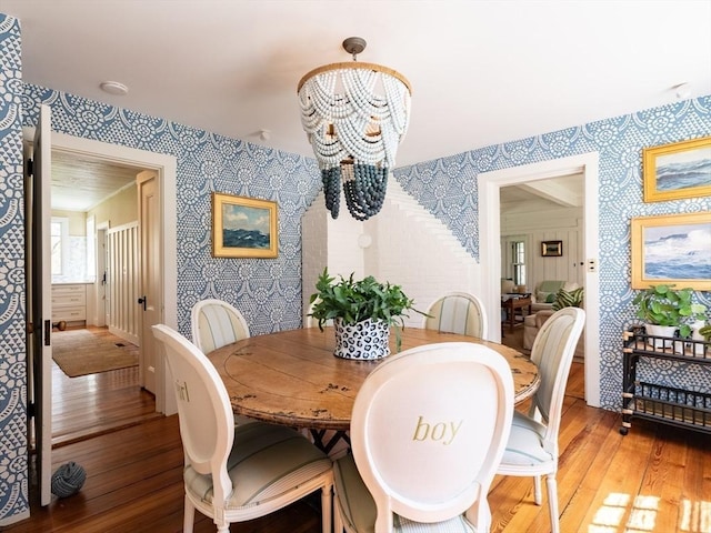 dining room featuring an inviting chandelier, light wood-type flooring, and wallpapered walls