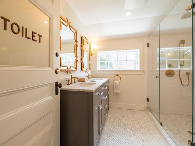 bathroom featuring a shower stall, double vanity, a wealth of natural light, and a sink