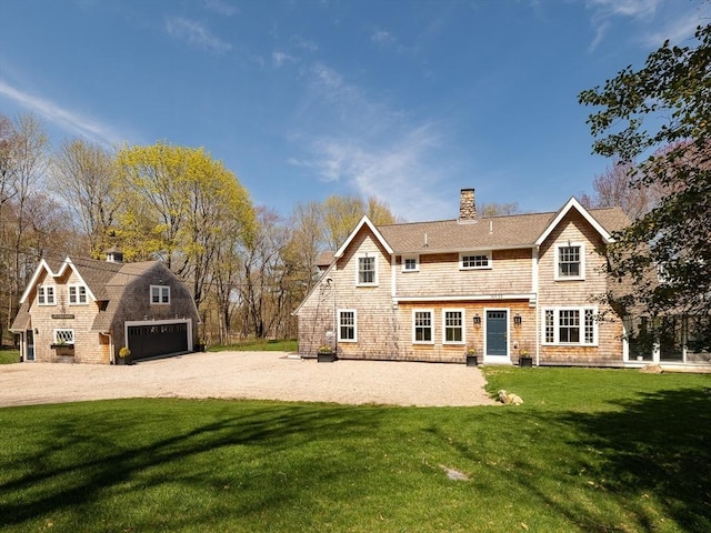 back of house featuring a lawn, a garage, driveway, and a chimney