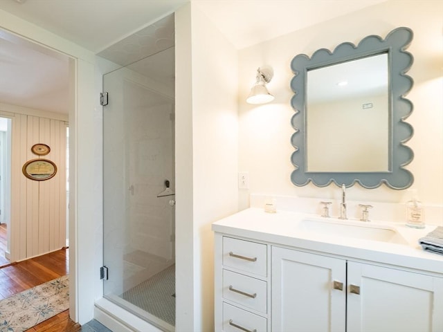bathroom with wood finished floors, a stall shower, and vanity