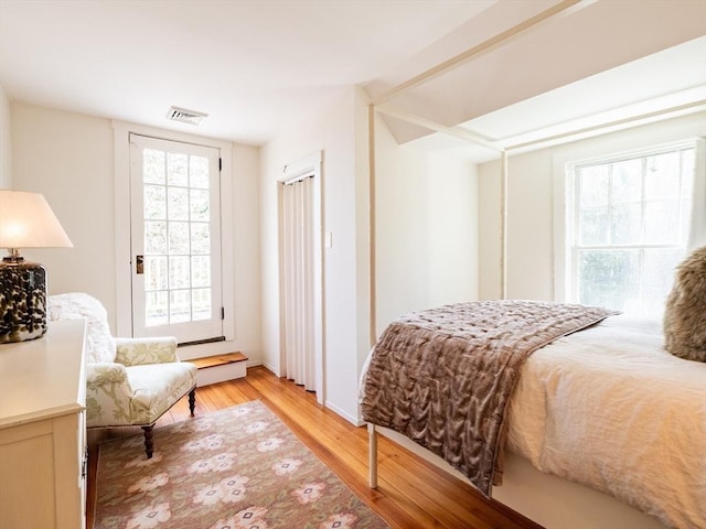 bedroom with visible vents, light wood-style floors, and access to outside