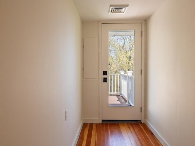 doorway to outside featuring baseboards, hardwood / wood-style flooring, and visible vents