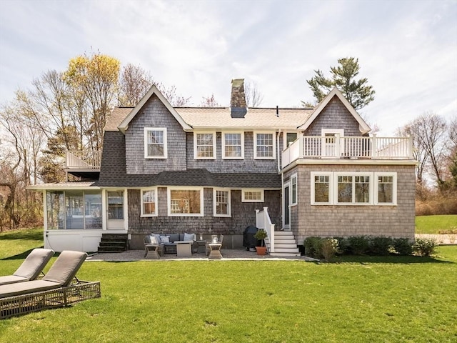 back of house featuring a balcony, a chimney, an outdoor living space, entry steps, and a yard