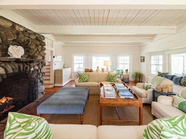 living area featuring wood ceiling, beamed ceiling, wood finished floors, and a fireplace