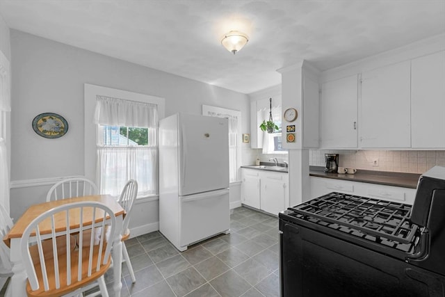 246 Railroad Ave, Norwood, MA 02062 - kitchen featuring freestanding refrigerator, black gas range, decorative backsplash, dark countertops, and white cabinetry