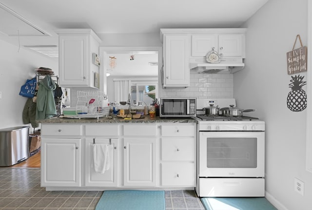 246 Railroad Ave, Norwood, MA 02062 - kitchen with stainless steel microwave, gas range gas stove, white cabinetry, backsplash, and under cabinet range hood