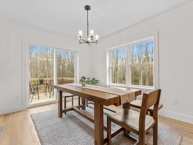 dining area with baseboards, an inviting chandelier, a wealth of natural light, and light wood-style flooring