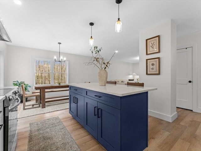 kitchen with stainless steel electric range oven, an inviting chandelier, light wood finished floors, and light countertops