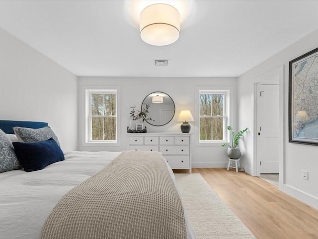 bedroom with visible vents, baseboards, and wood finished floors