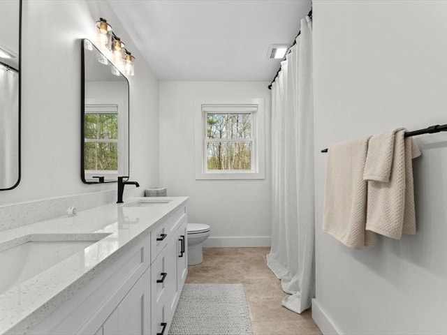 full bathroom with double vanity, a sink, a healthy amount of sunlight, and toilet