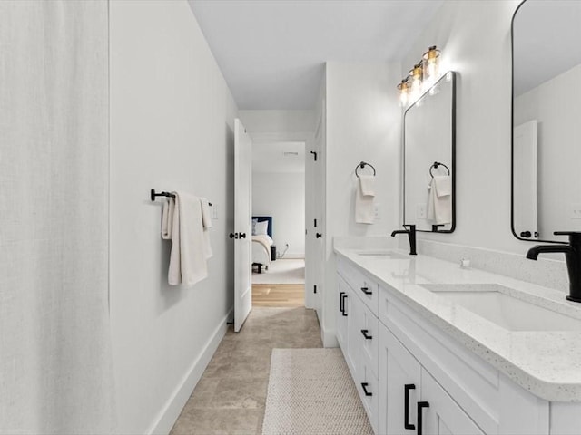 full bath with baseboards, a sink, ensuite bath, and double vanity