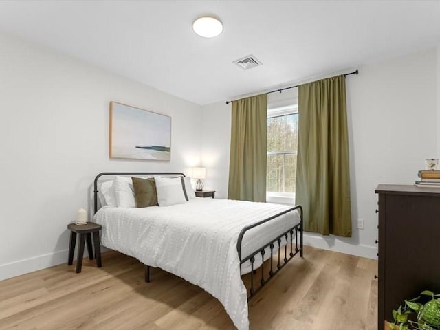 bedroom with visible vents, baseboards, and wood finished floors