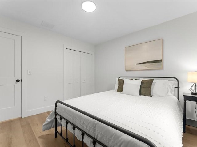 bedroom with a closet, baseboards, visible vents, and light wood-type flooring