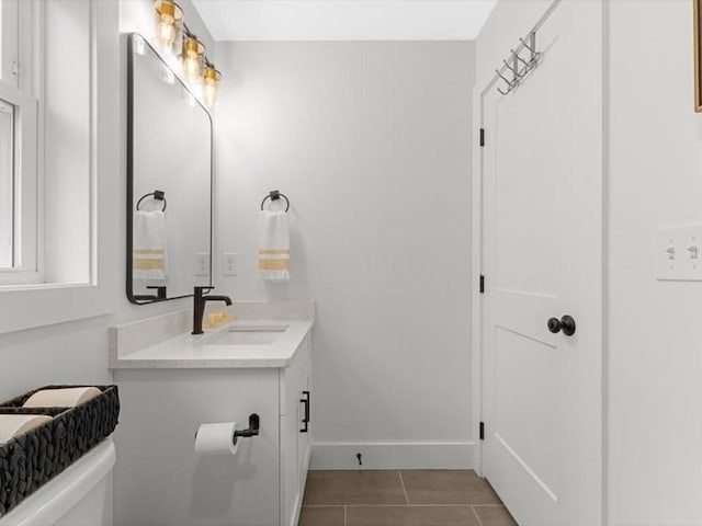 half bath with vanity, baseboards, tile patterned floors, and toilet