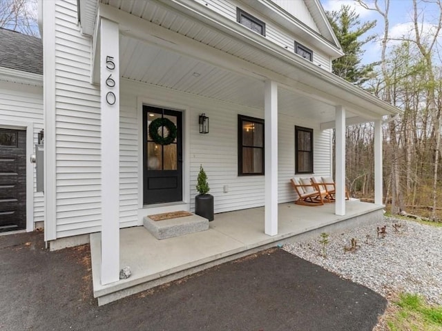 property entrance with covered porch and roof with shingles