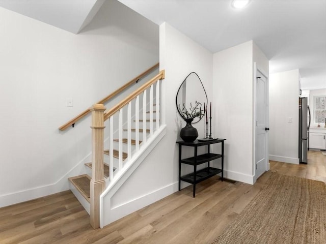 staircase featuring baseboards and wood finished floors