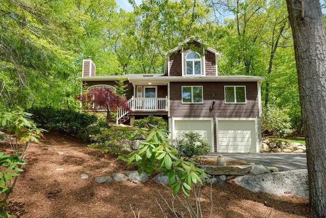 view of front of house with driveway, an attached garage, and a chimney