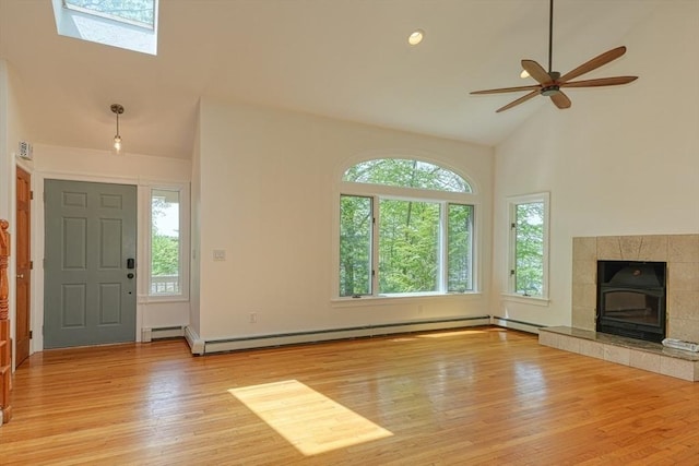 unfurnished living room with plenty of natural light, light wood-style floors, high vaulted ceiling, baseboard heating, and a ceiling fan