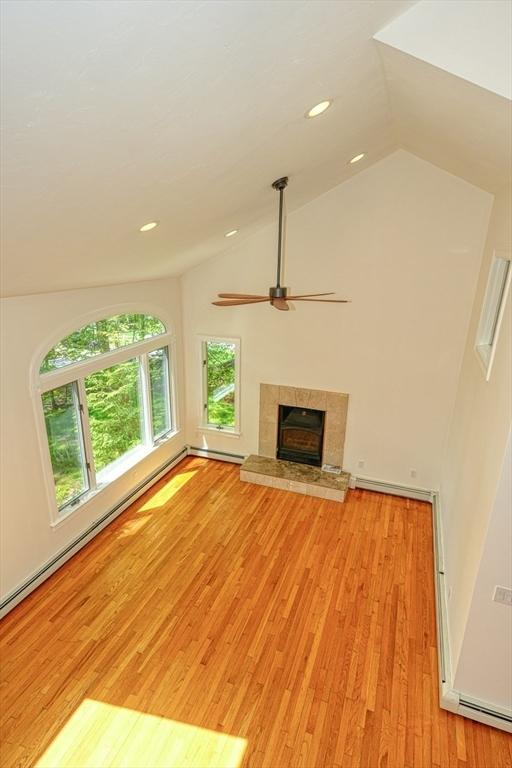 unfurnished living room with vaulted ceiling, light wood-style flooring, ceiling fan, a tiled fireplace, and recessed lighting