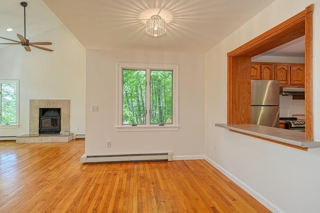unfurnished living room featuring a baseboard radiator, a ceiling fan, light wood finished floors, and baseboards