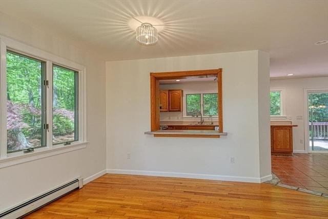 spare room featuring a baseboard heating unit, a sink, baseboards, wood finished floors, and recessed lighting