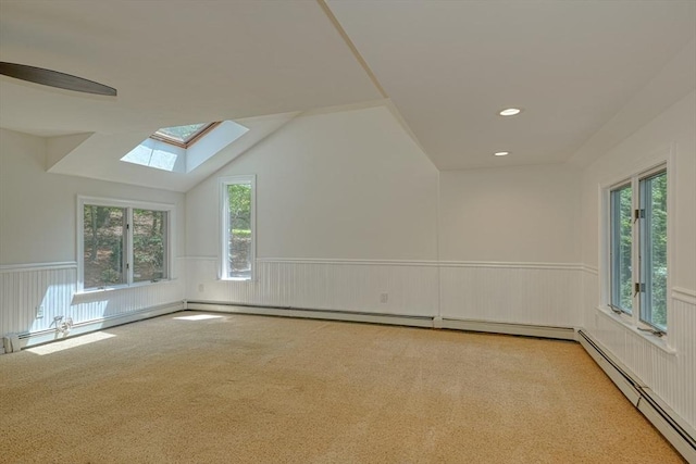 bonus room with baseboard heating, a skylight, a wainscoted wall, plenty of natural light, and carpet flooring
