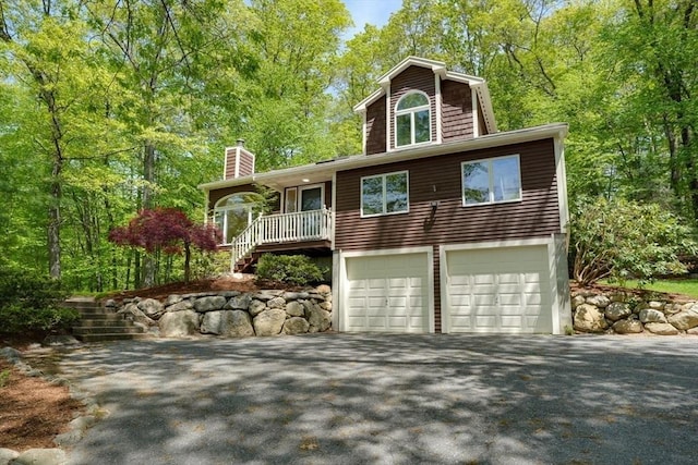 view of front facade with stairs, driveway, a garage, and a chimney