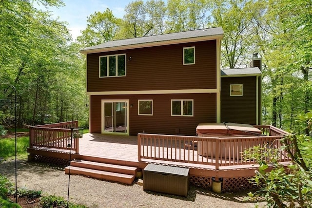 rear view of house with a hot tub, a chimney, and a wooden deck