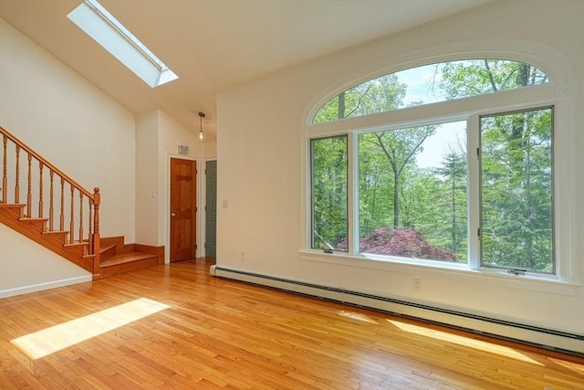 foyer entrance featuring a baseboard heating unit, a skylight, light wood-type flooring, stairway, and high vaulted ceiling