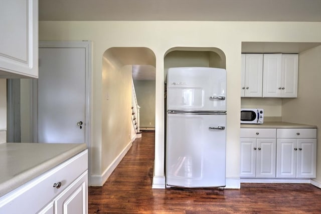 kitchen featuring white appliances, dark wood-style floors, light countertops, and white cabinetry